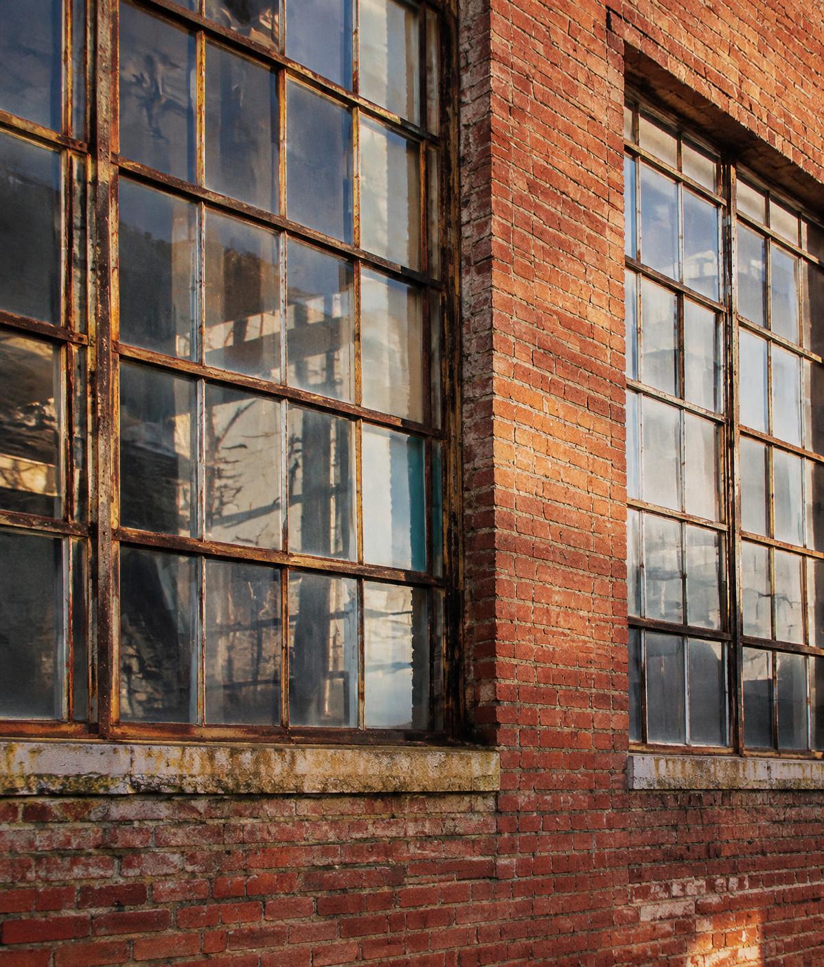 Illustrative image: weathered brick wall and steel factory windows